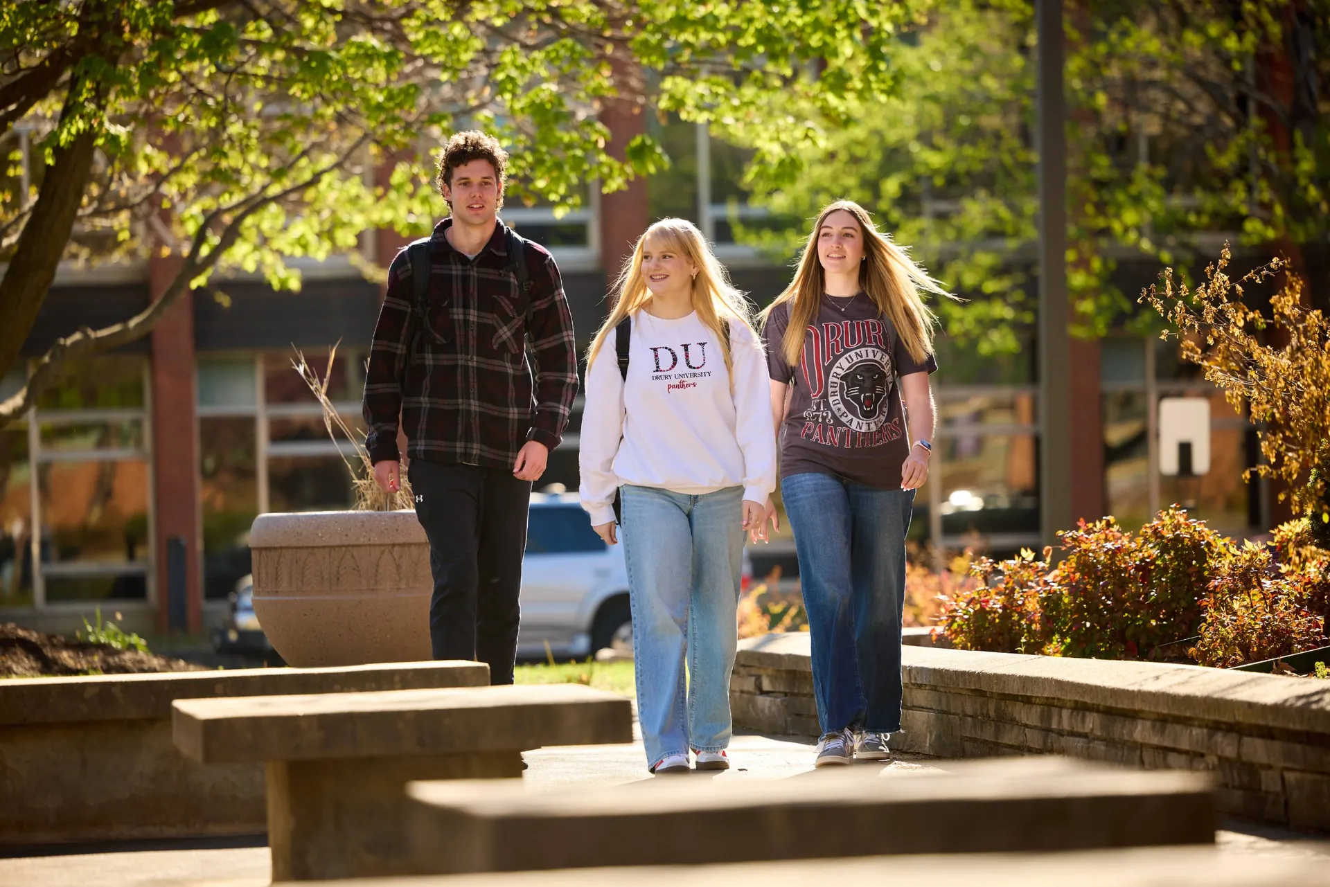 Three Drury students walking across campus on a sunny autumn day